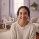 Headshot portrait of a smiling young mother with diverse features, looking confidently at the camera in a warm, cream-colored